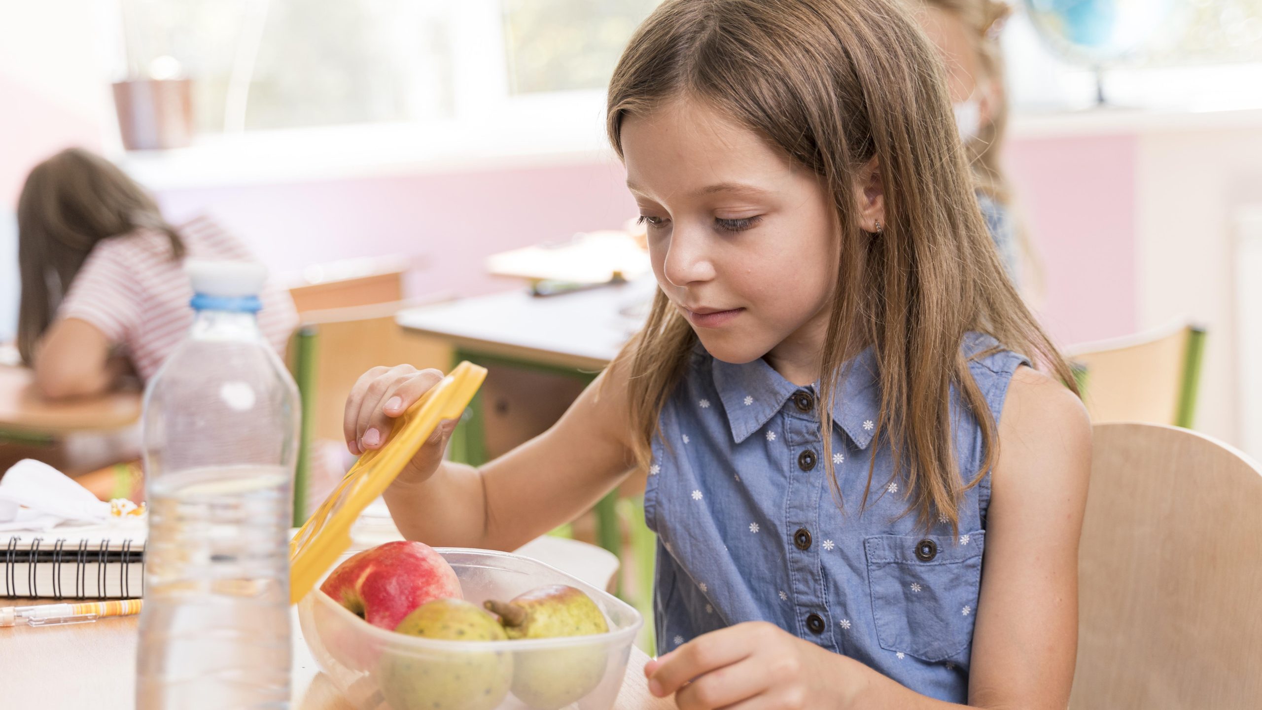Educação alimentar: criança abrindo tupperware com frutas.