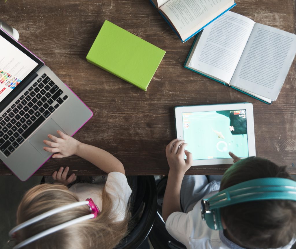 Anos finais do ensino fundamental: crianças com tablet e notebook em sala de aula.